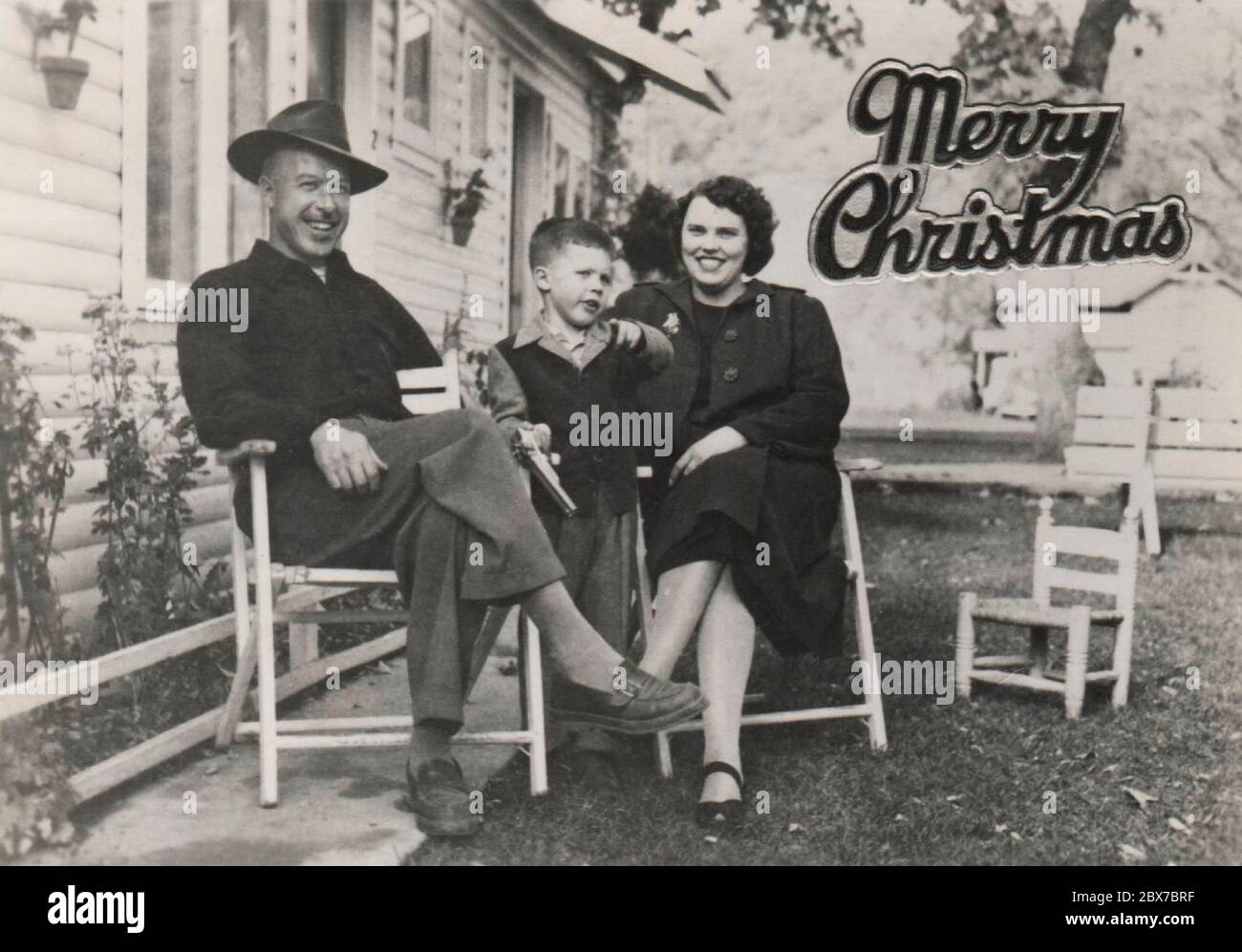 A retro Christmas Card, from a family in Oregon, circa 1948, showing a husband, wife, and small boy, sitting in their yard. Stock Photo
