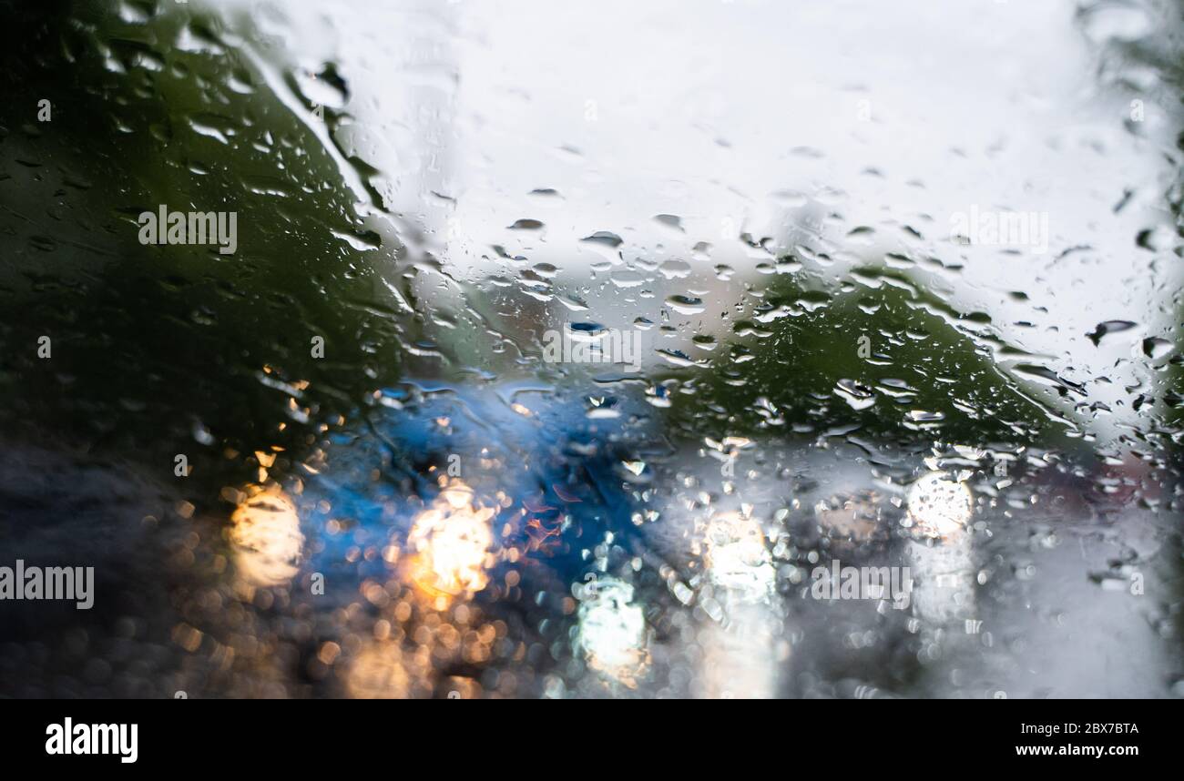 Raindrops on a windscreen glass with a blurred night city lights at the ...