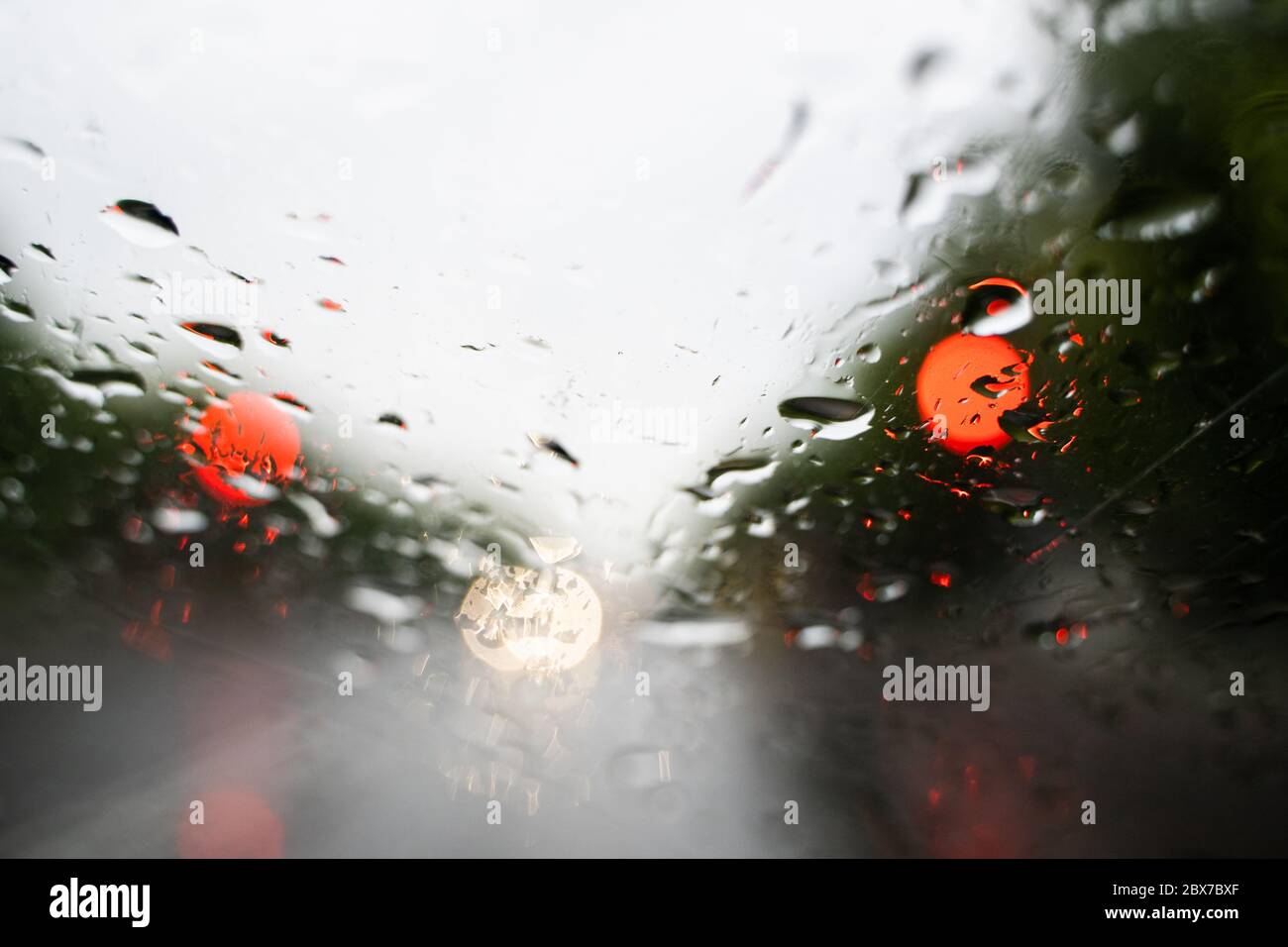 Raindrops on a windscreen glass with a blurred night city lights at the ...