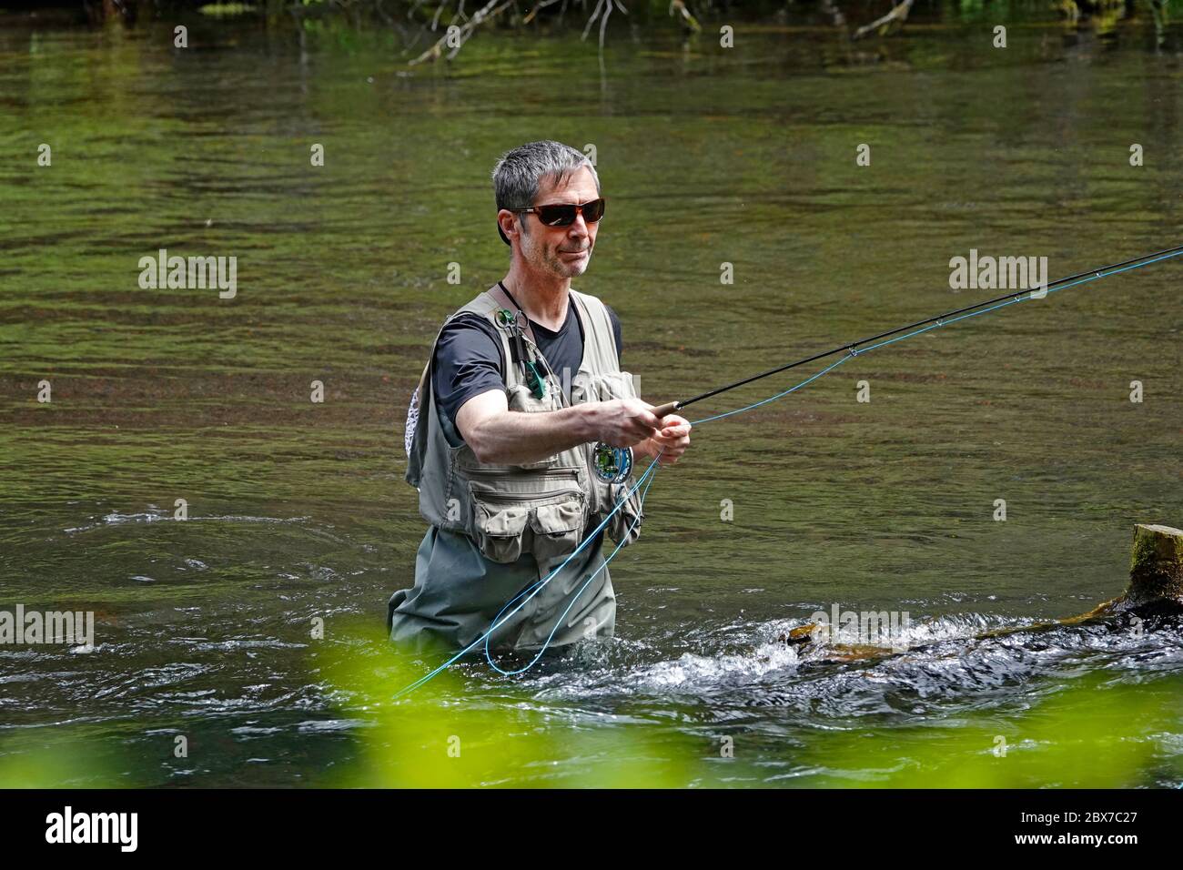 A trout fisherman fly fishing for rainbow trout with a fly rod on the