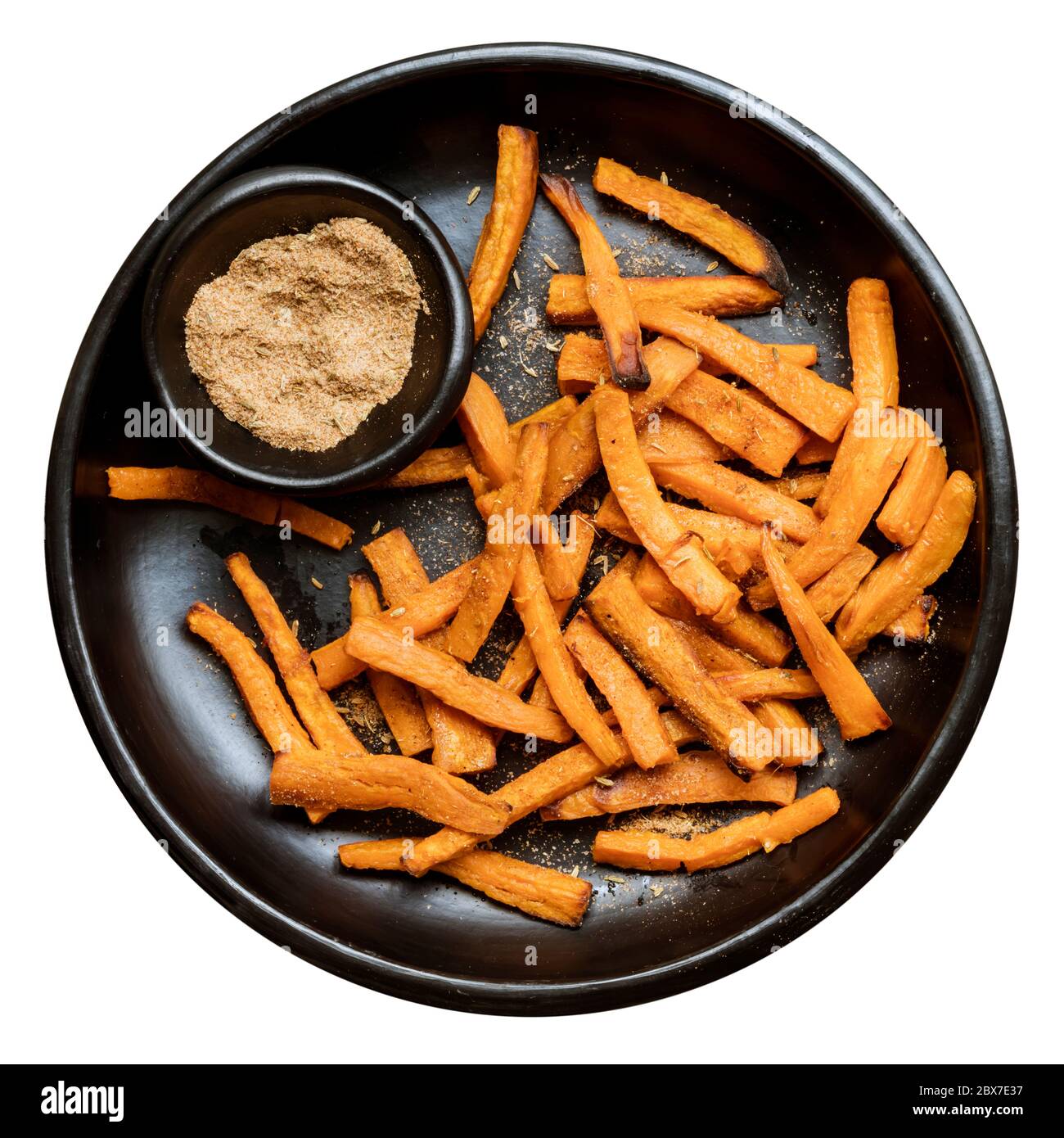 Sweet potato fries with spiced salt on black dish, isolated. Top view