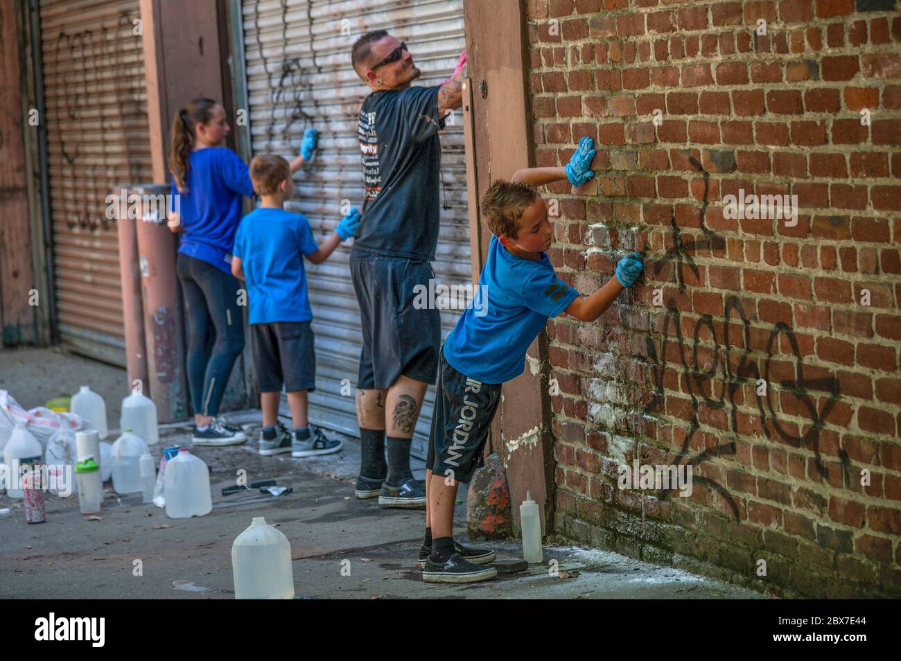 June 3, 2020, Sacramento, California, USA: Joshua Vanek cleans graffiti  with his son Weston Vanek, 10, right, daughter, Holley Vanek, 11, left, and  Hunter Varek, 7, center, along Q Street in Sacramento