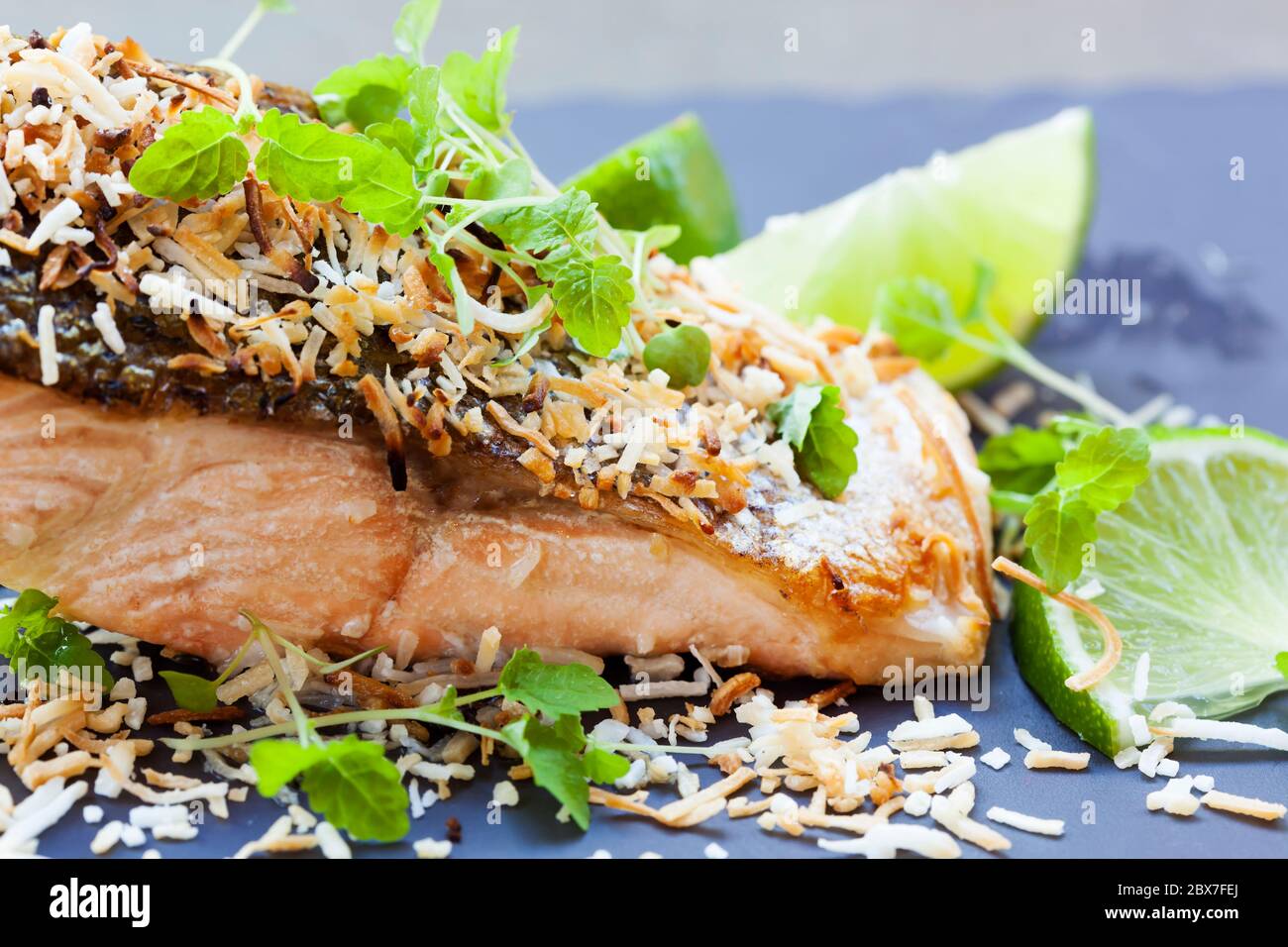 Salmon grilled with lime and toasted coconut.  Garnished with micro herbs. Stock Photo