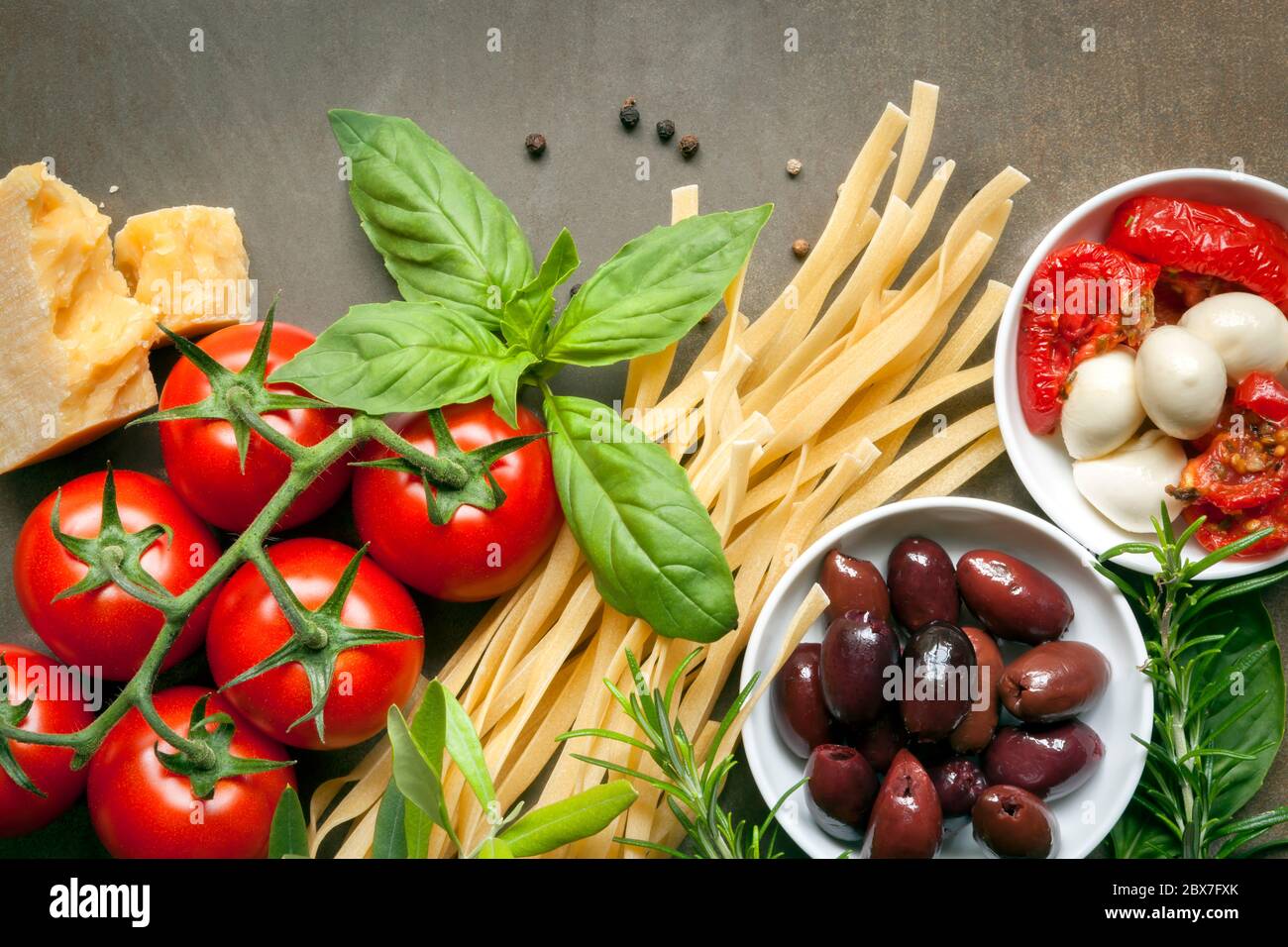 Italian food background, over slate.  Top view. Variety of ingredients, including pasta, tomatoes, basil, olives, parmesan, mozzarella, garlic, and he Stock Photo