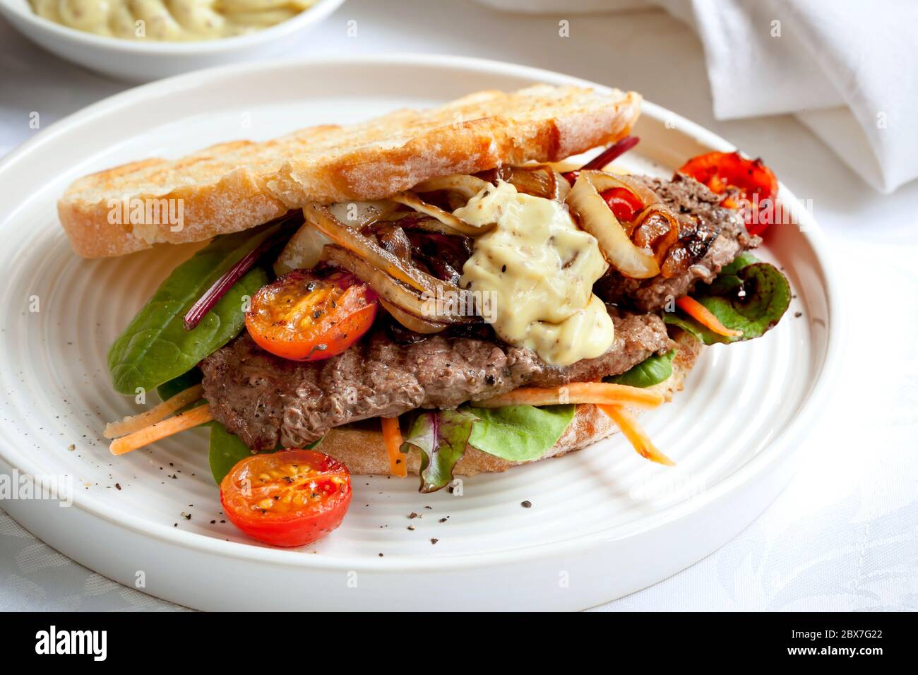 Steak sandwich with salad, grilled onions and aioli Stock Photo Alamy