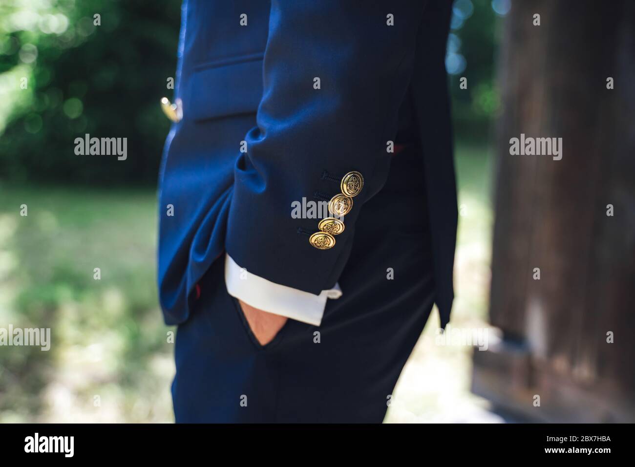 Side view of man in blue suit with hand in pocket. Close up of jacket