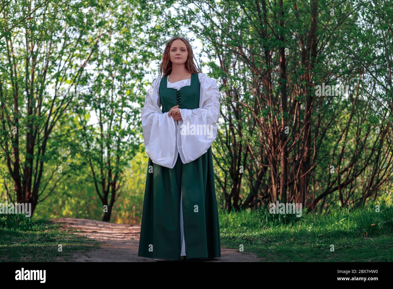 Beautiful medieval young woman in traditional historical female green and  white costume at nature. Fantasy girl in long dress or gown walking at path  Stock Photo - Alamy