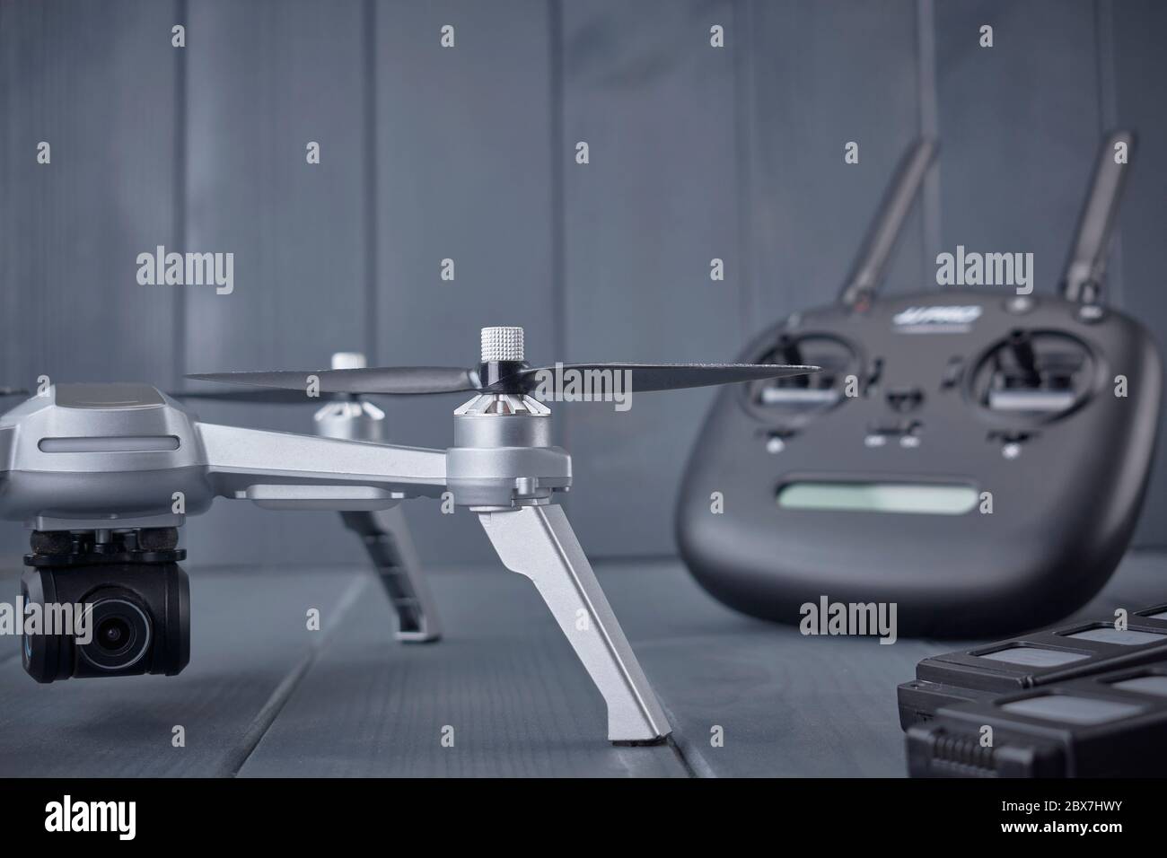 Close-up of quad-engine drone mounted camera and dual frequency radio control remote control in the background on gray wooden background Stock Photo