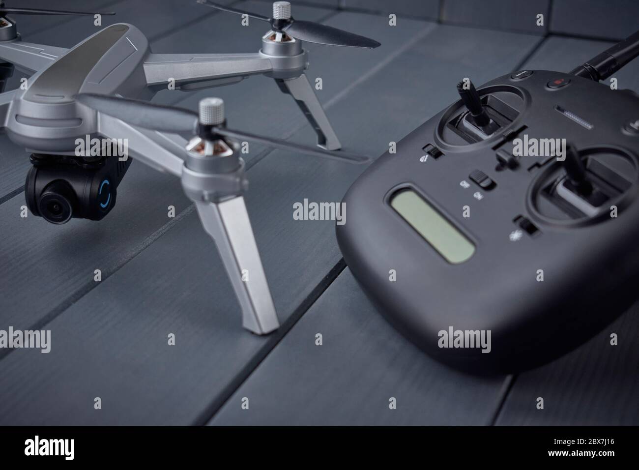 Close-up of quad-engine drone mounted camera and dual frequency radio control remote control in the background on gray wooden background Stock Photo