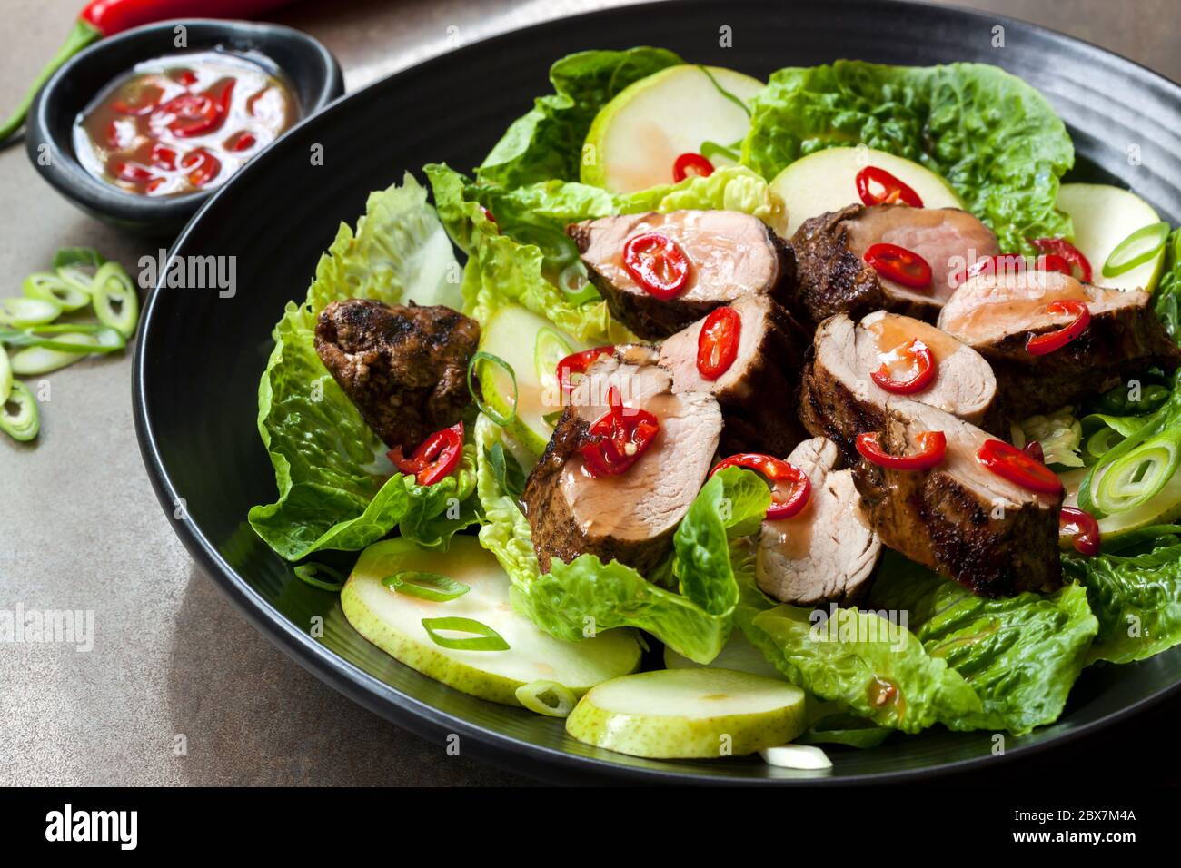 Pork salad with chili, pear and cos lettuce.  Grilled fillet marinated in plum sauce. Stock Photo