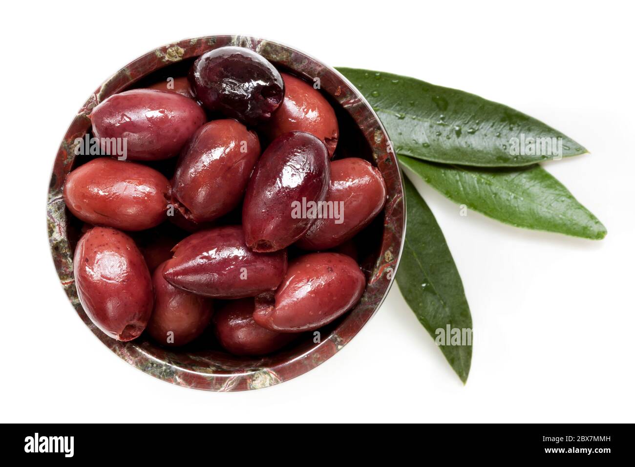 Pitted black kalamata olives in small bowl with leaves, isolated.  Top view. Stock Photo