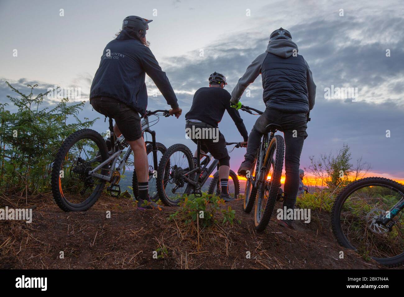 Mountain bikers gathering on hilltop at sunset in UK Stock Photo