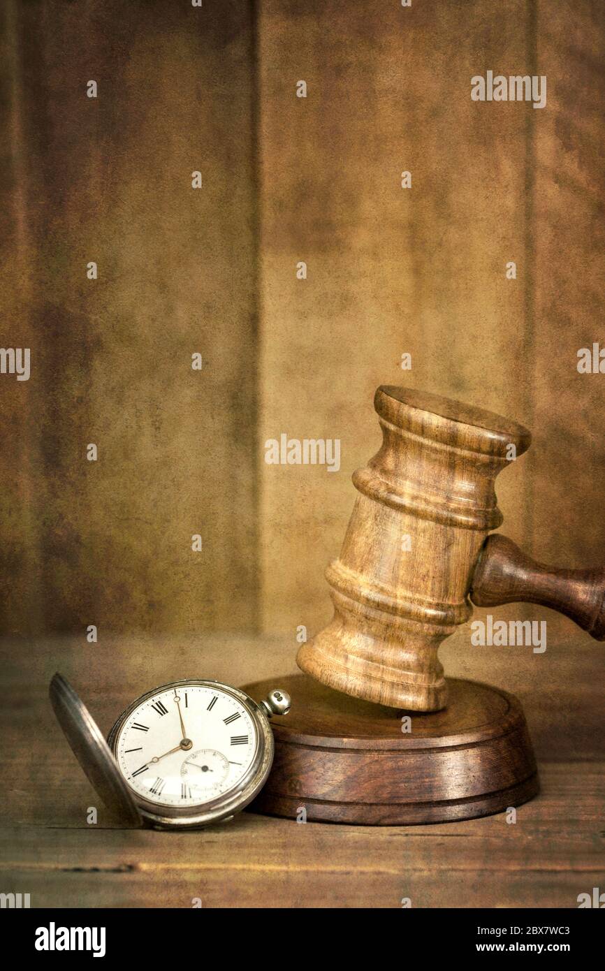 Time and justice concept.  Old pocket watch with wooden gavel, with timber background.  Added grunge effects. Stock Photo