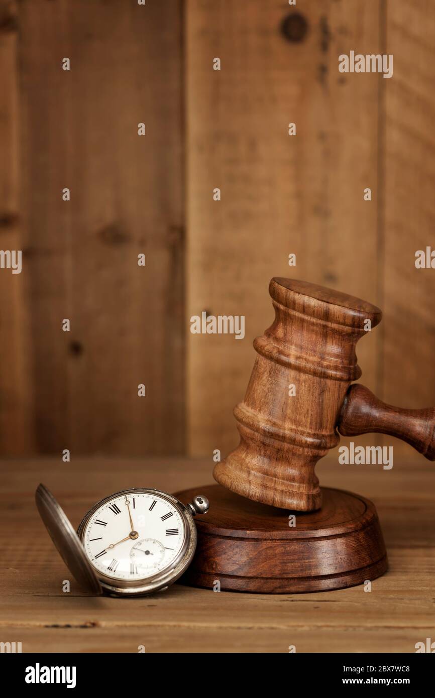 Old Pocketwatch and wooden gavel, over timber background. Stock Photo