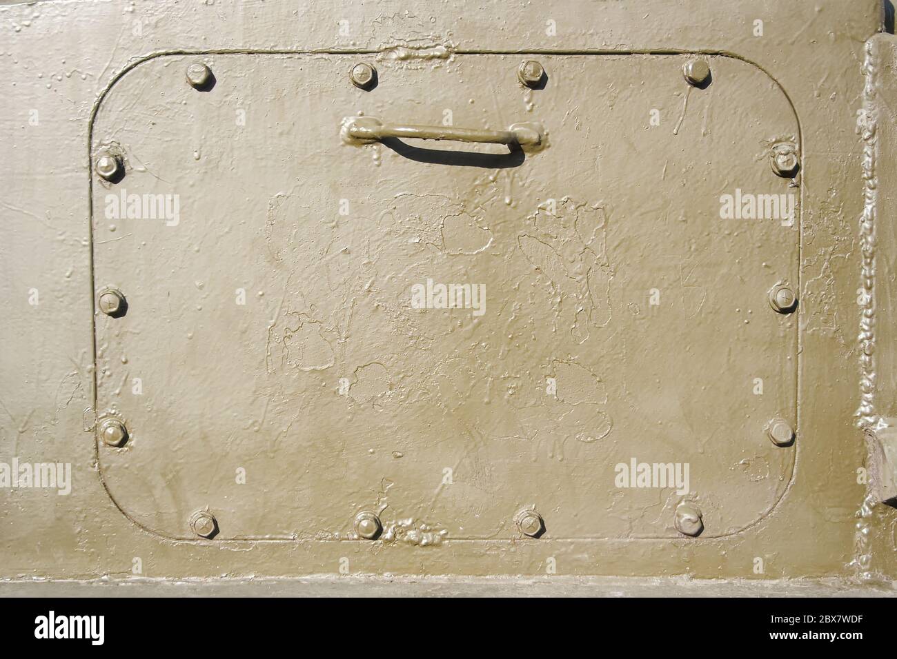 Closeup photo of a yellow metal armored tank hatchway. Stock Photo
