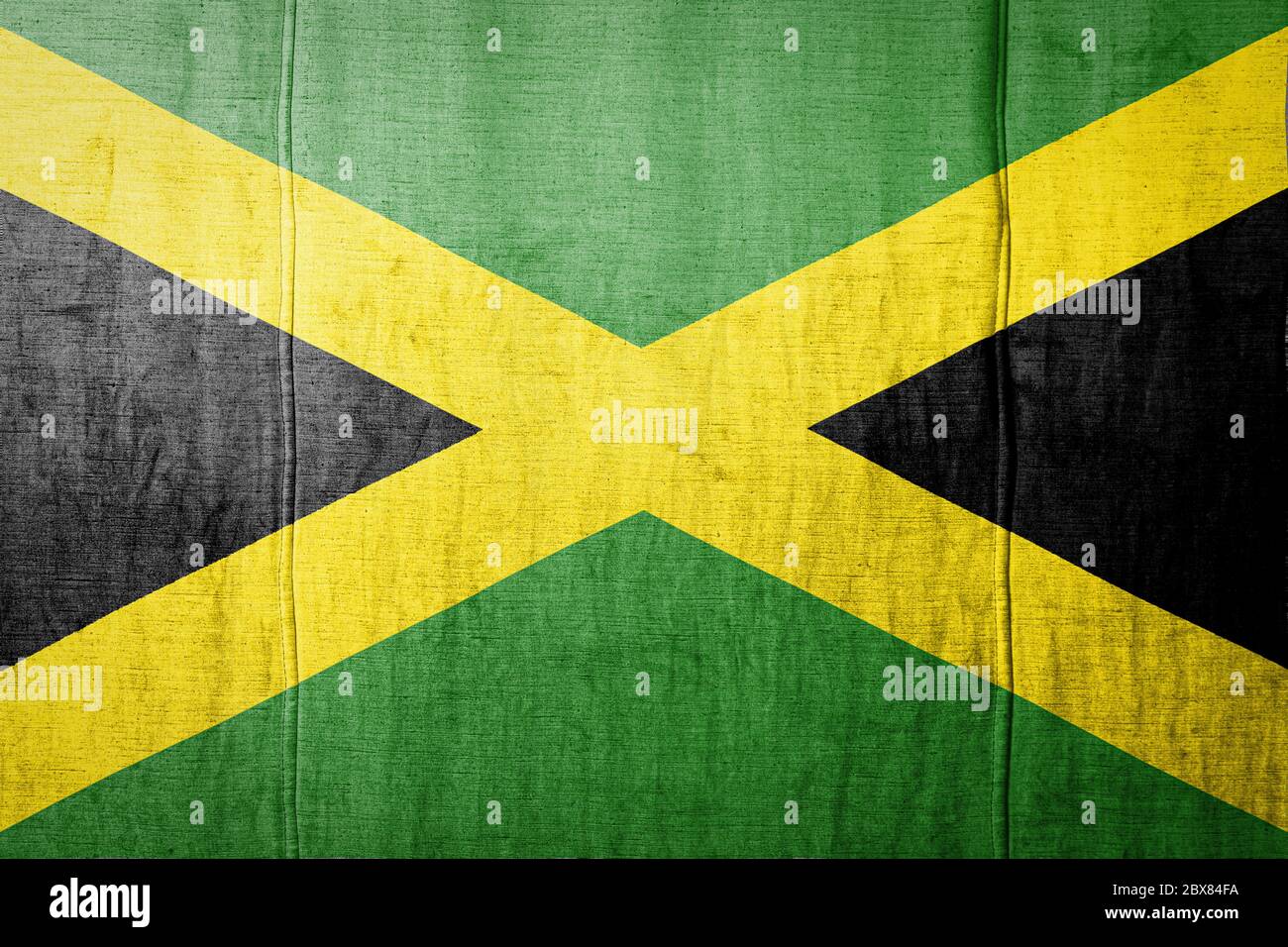 National flag of Jamaica  depicting in paint colors on old textile. Flag  banner on  fabric texture background. Stock Photo