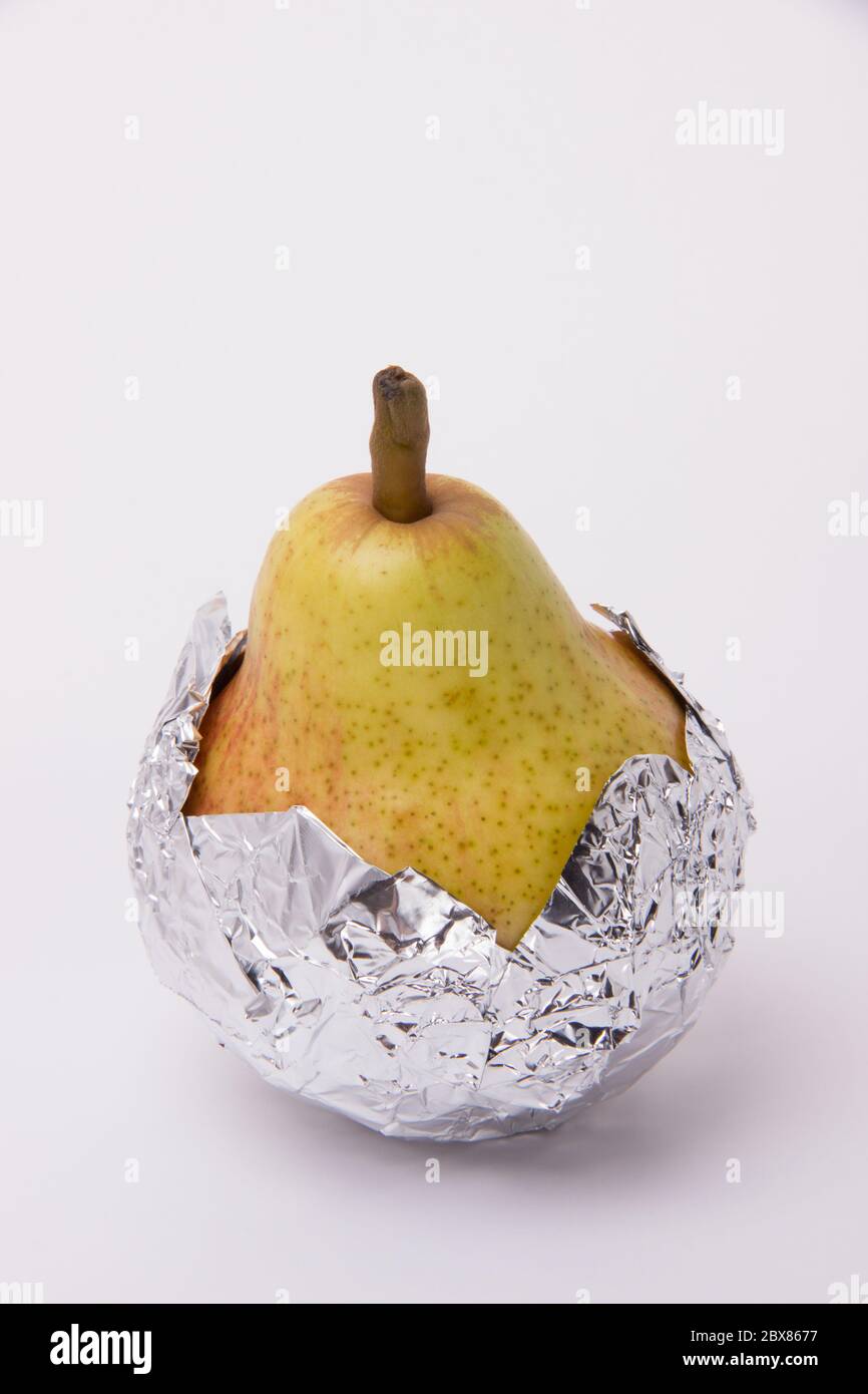 Yellow juicy pear wrapped in foil on a white background Stock Photo Alamy