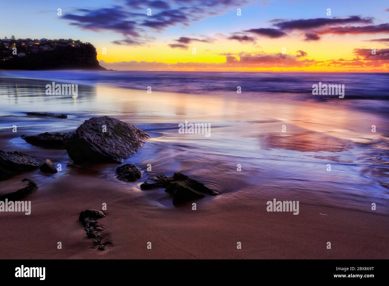 Quiet sandy Northern Beach in Sydney on Pacific ocean coast at sunrise with spectacular colours. Stock Photo