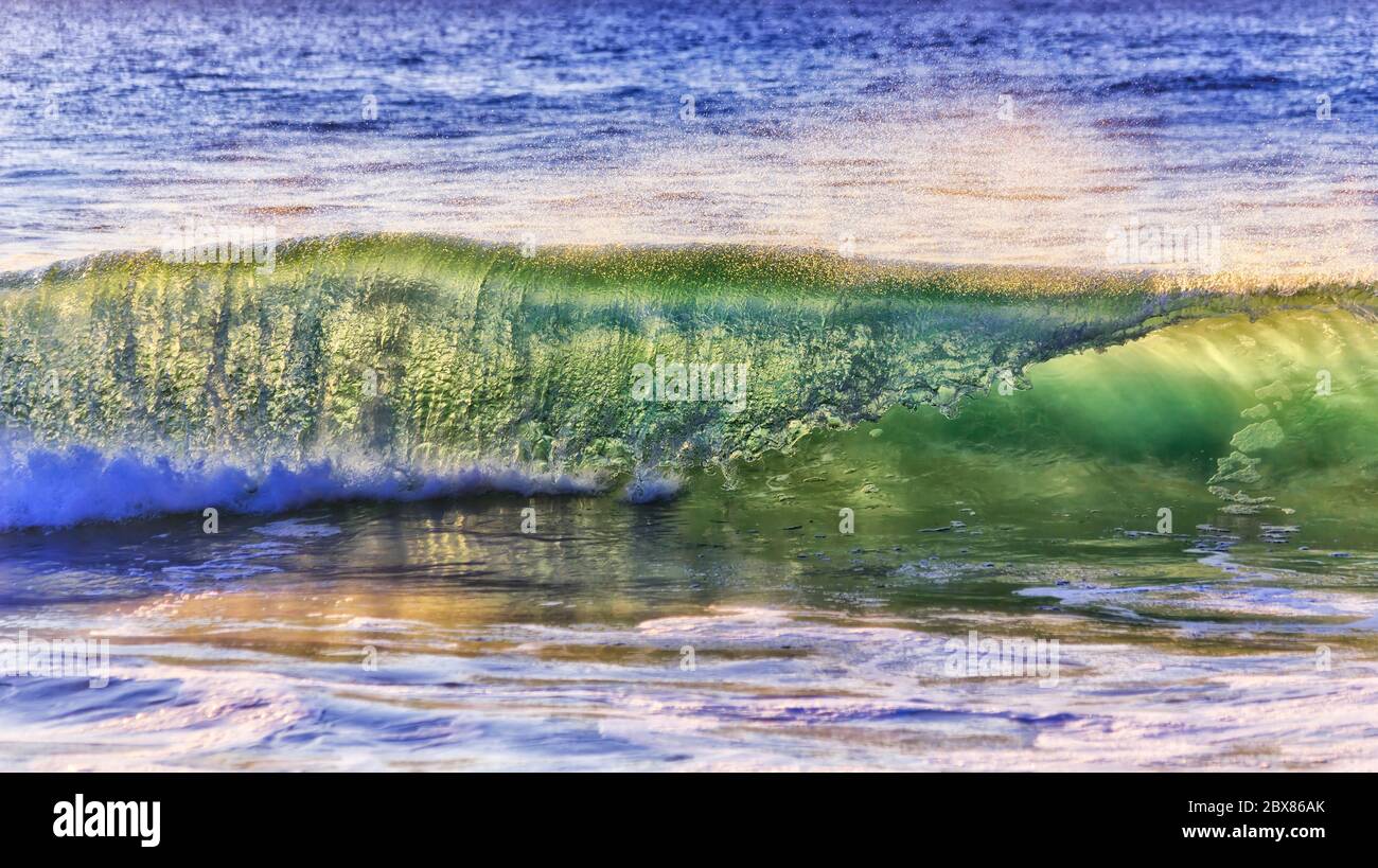 Fast rolling swirling wave streaming to Sydney Northern beach from open Pacific ocean in bright morning light. Stock Photo