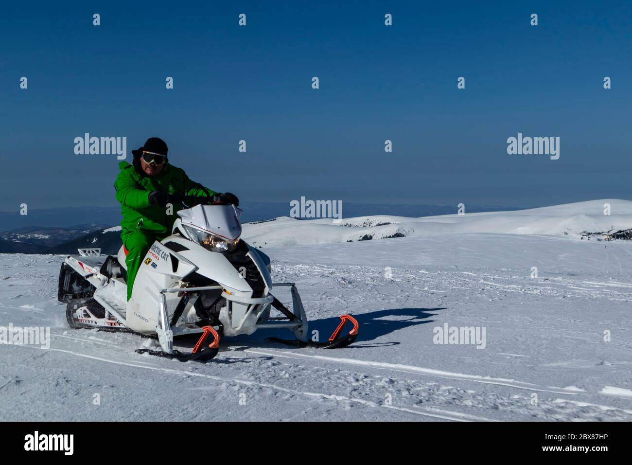 Rider on the snowmobile in the mountains ski resort. A man is riding snowmobile in mountains Stock Photo