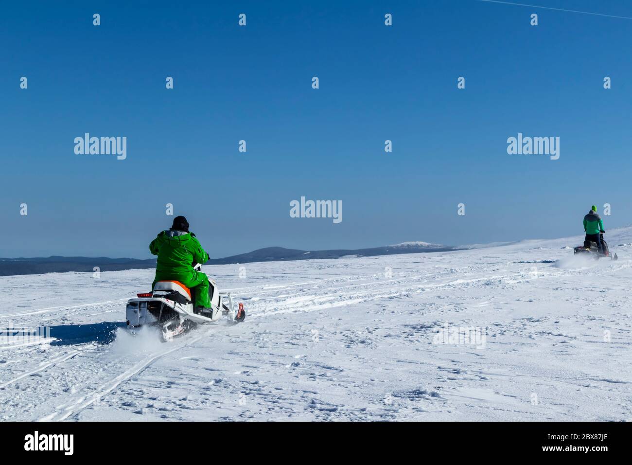 Rider on the snowmobile in the mountains ski resort. A man is riding snowmobile in mountains Stock Photo