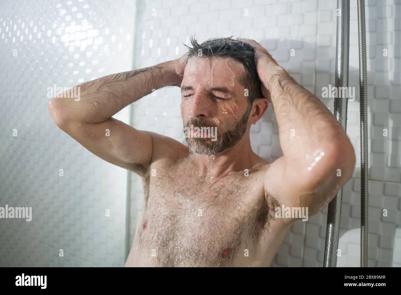home bathroom dramatic portrait of young attractive sad and depressed man in the shower leaning