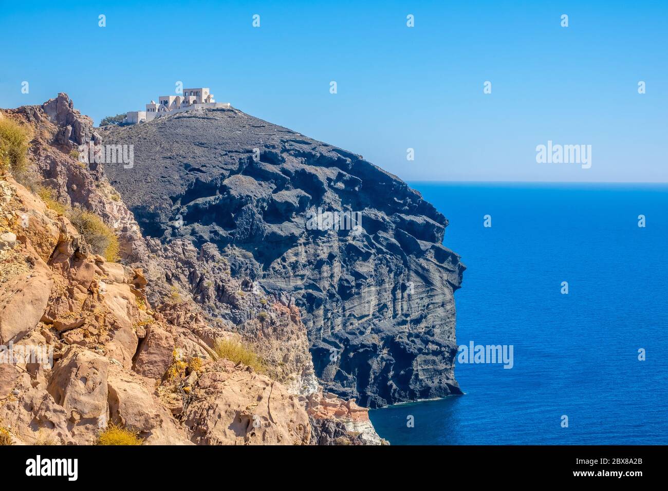 Greece. Sunny summer day on the rocky shore of the Mediterranean Sea. Abandoned hotel construction on top of a blue cliff Stock Photo