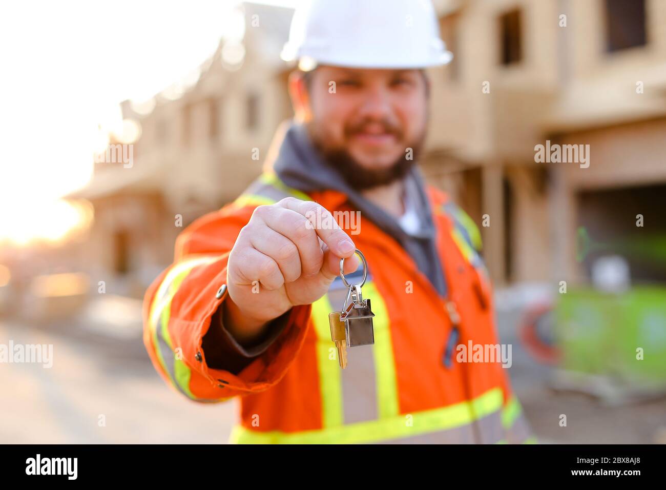 Focus on keys from new home given by foreman in helmet. Stock Photo
