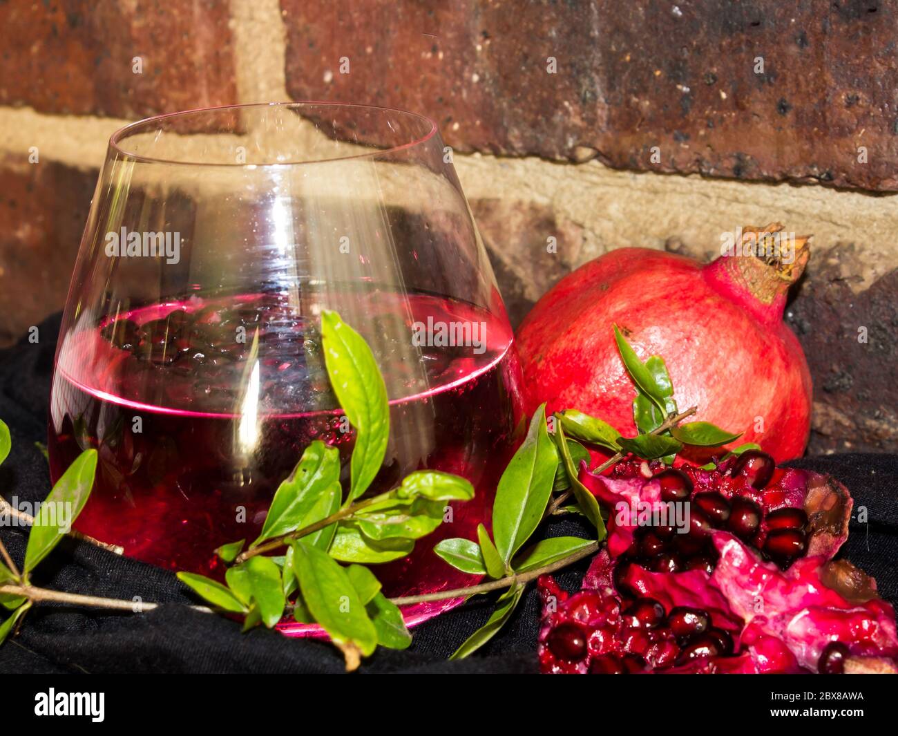 Still life of a red, pomegranate flavored gin and tonic cocktail