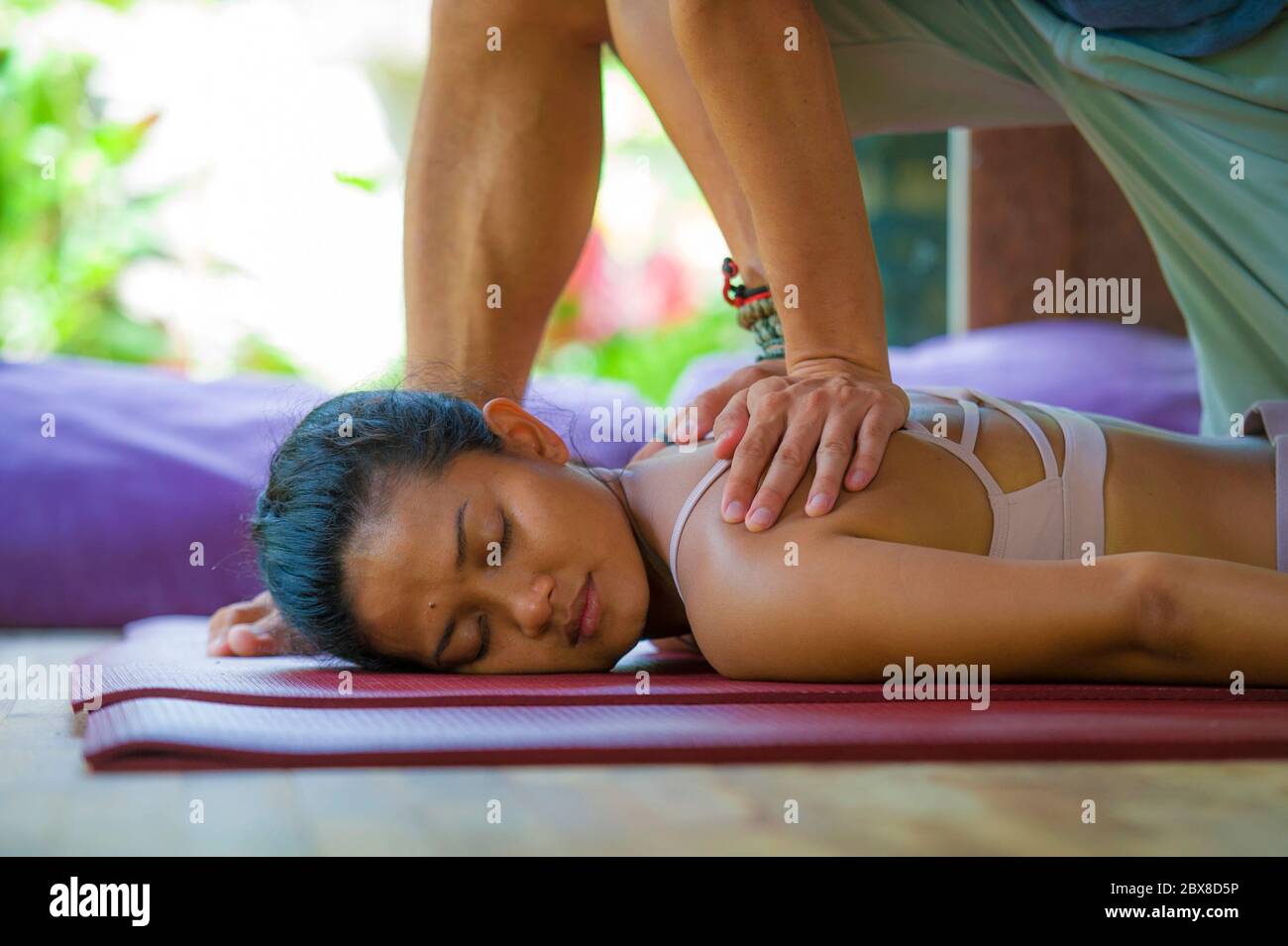 young beautiful and exotic Asian Balinese woman lying on studio mat  receiving traditional Thai massage by masseur at tropical wellness spa  garden in h Stock Photo - Alamy