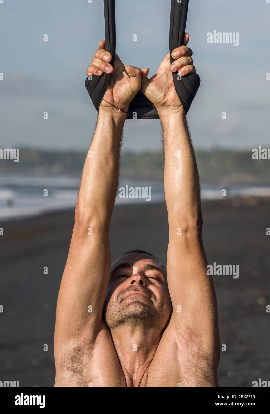 outdoors portrait of man practicing aero yoga workout at the beach hanging from rope swing above the sea training body balance and flexibility in hea Stock Photo Alamy