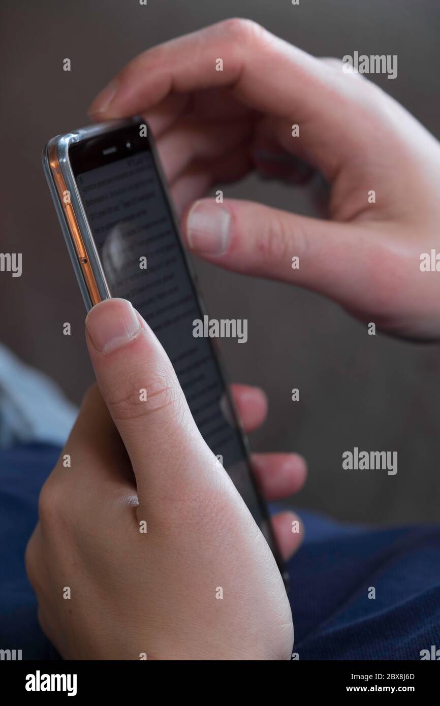 Man lying on the couch and scrolling and reading messages on his