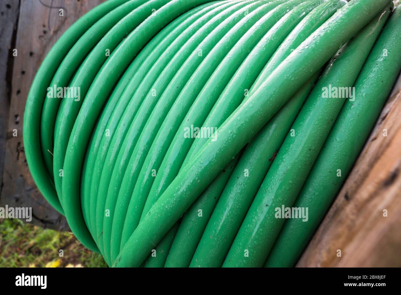 Wooden Coil Of Green Electric Cable Outdoor. Focus On Cables In 