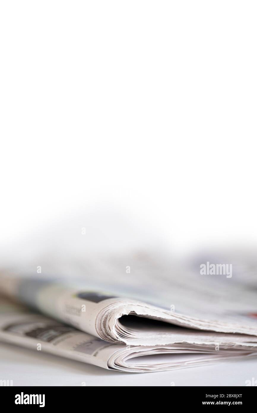 Folded newspapers on white table with narrow depth of field. Vertical image. Copy space Stock Photo