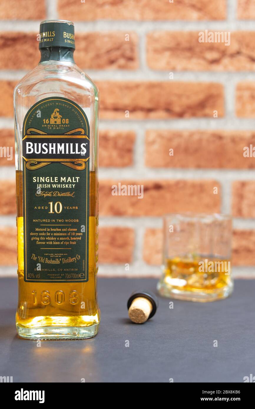 A bottle of Bushmills single malt whiskey with a glass against a clinker  background Stock Photo - Alamy