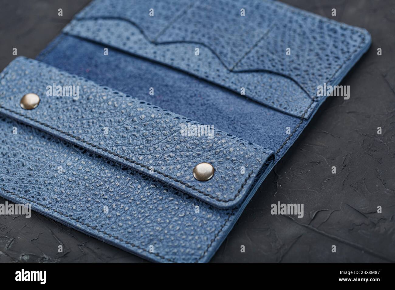 Blue leather wallet on a black textured background. Stock Photo