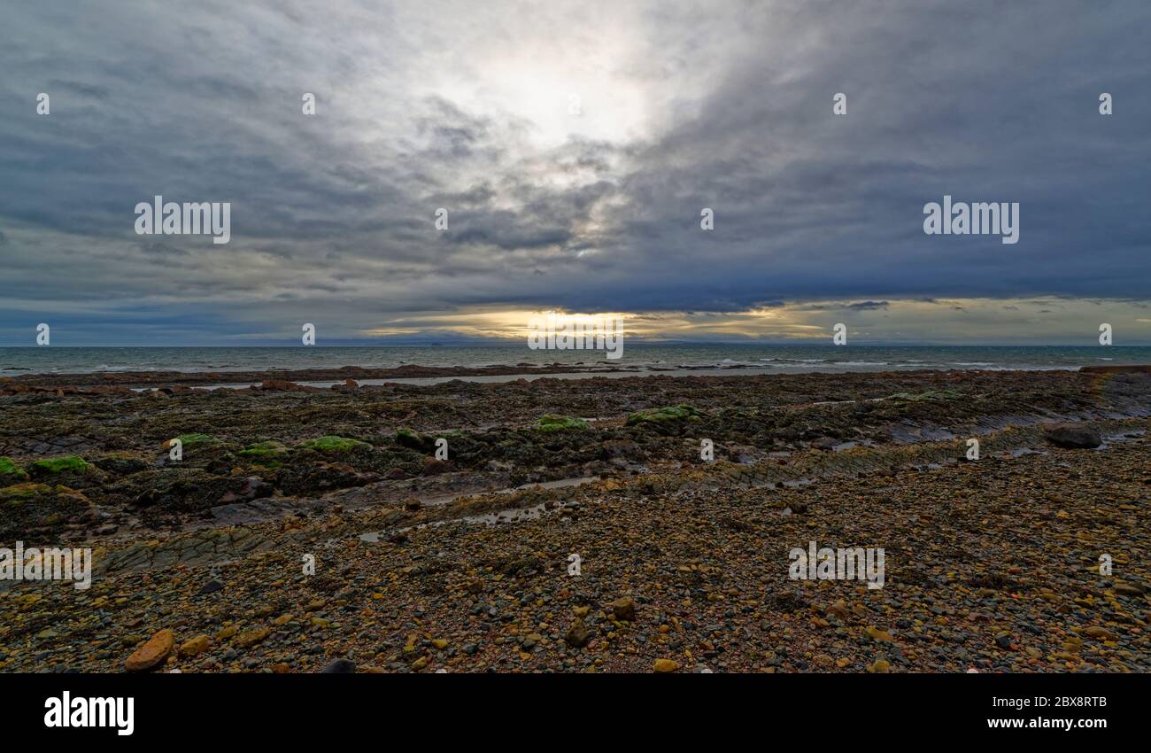 Looking across the Firth of Forth towards North Berwick from St Monan's on the Fife Coast, on a wet winter evening with the pale yellow Sunset. Stock Photo