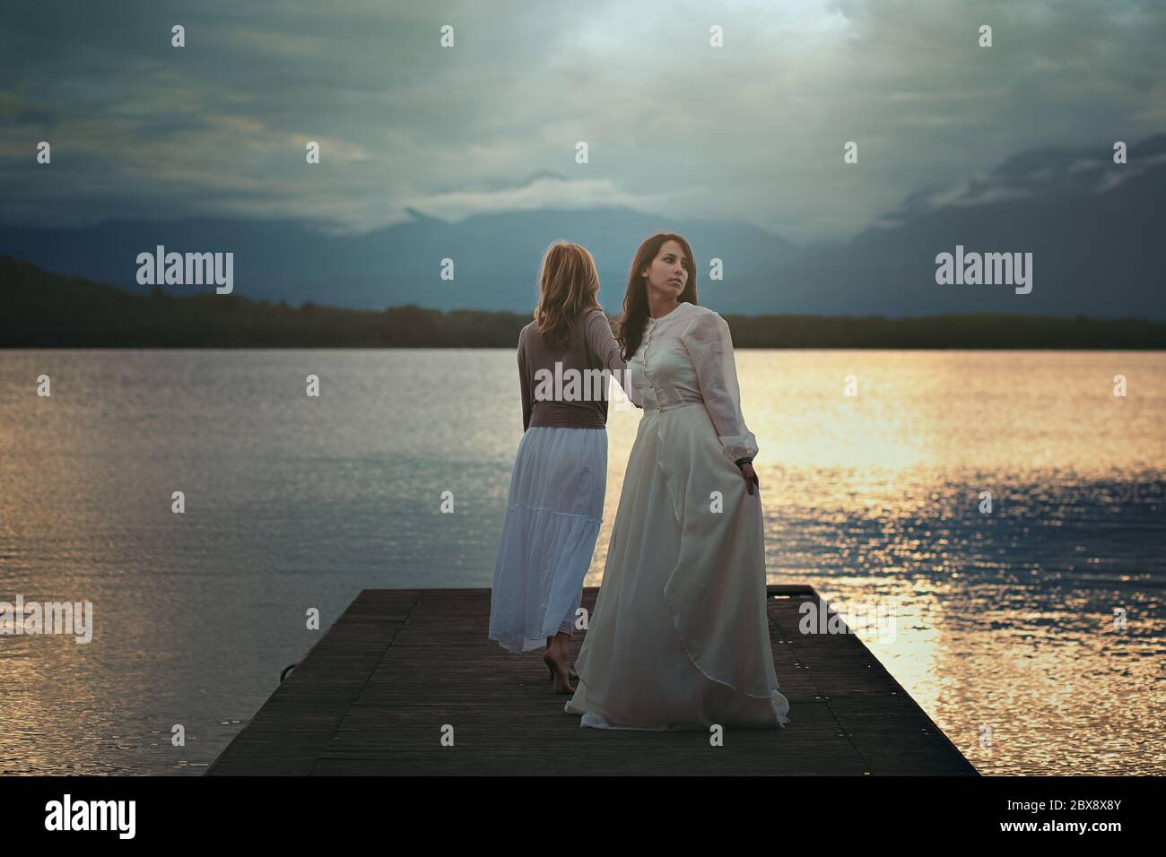Two women on a lake pier . Surreal and ethereal Stock Photo
