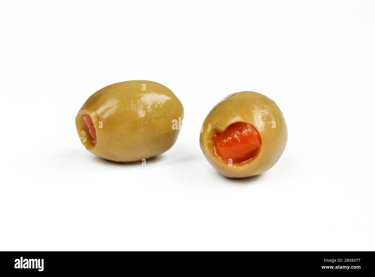 Two green olives stuffed with red pepper. Wet filled olives isolated