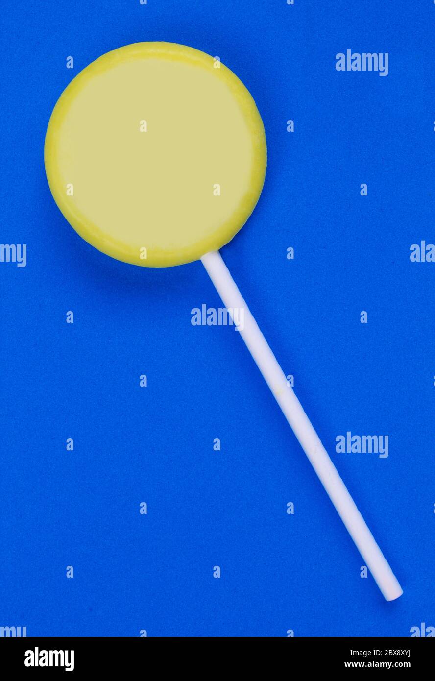Simple yellow lollipop isolated on blue background. Stock Photo