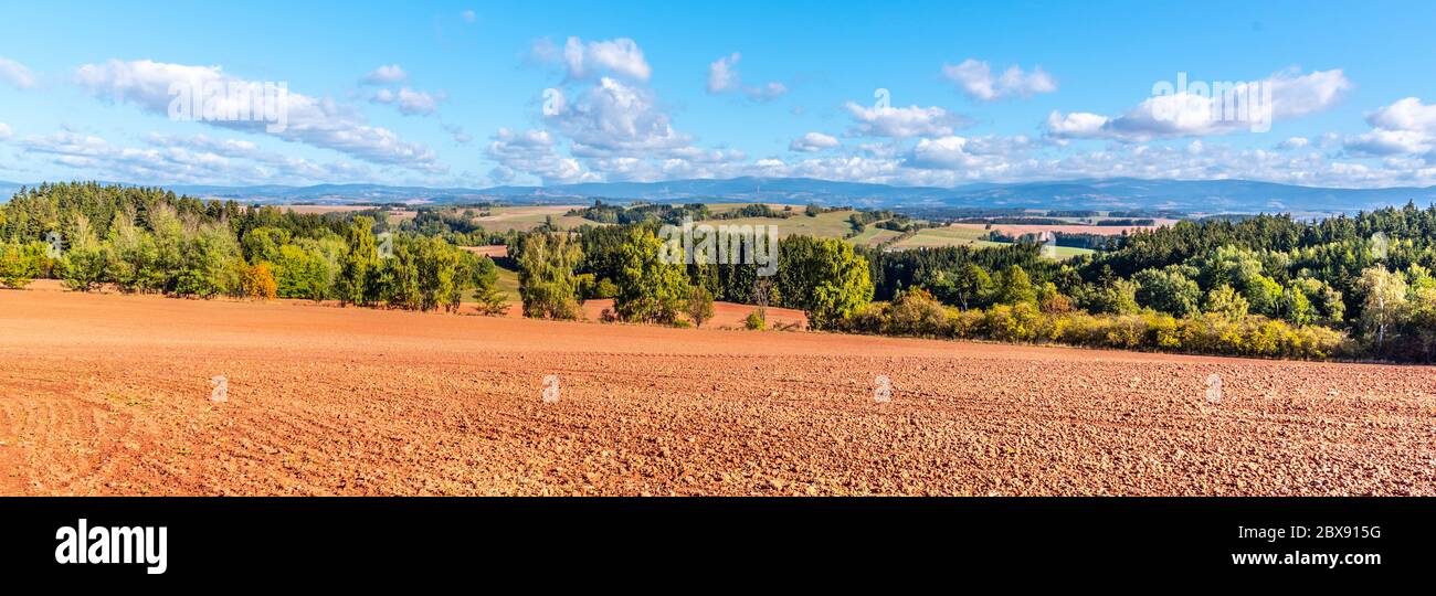 Typical red soil of countryside around Nova Paka. Agricultural Landscape with Giant Mountains on the background. Czech Republic. Stock Photo
