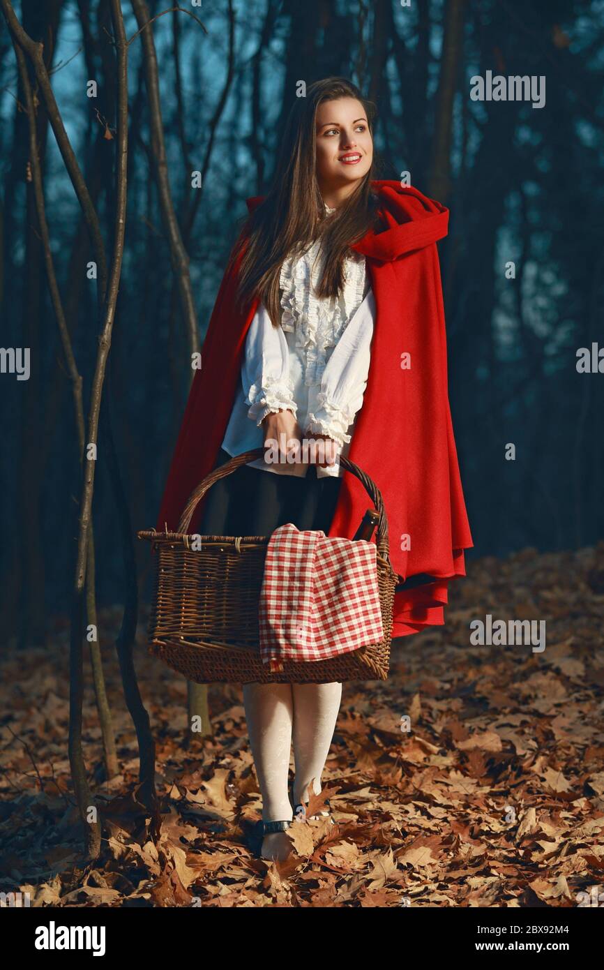 Smiling Little Red riding hood in the forest at night . Fairy tale and fantasy Stock Photo