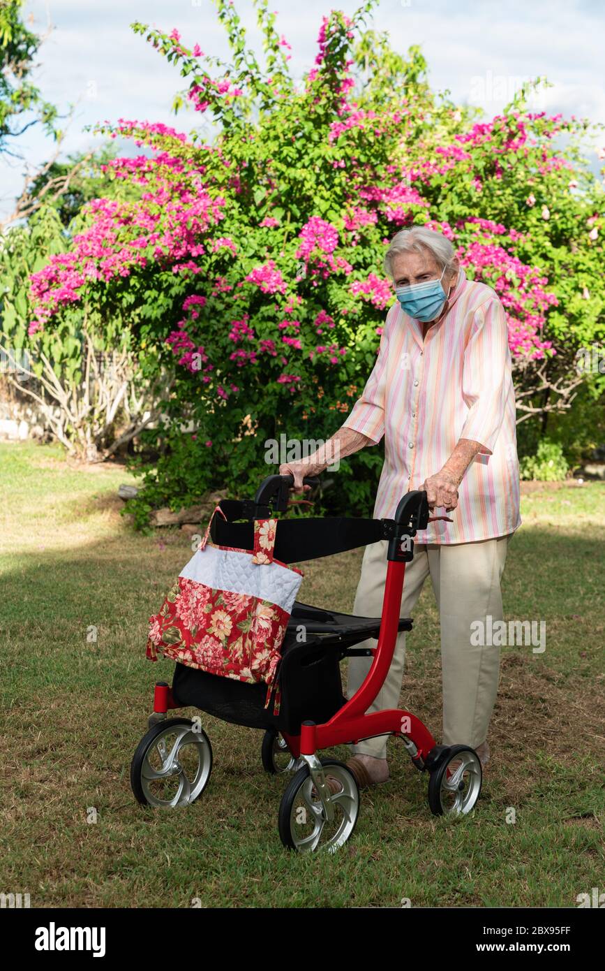 Elderly lady wearing mask getting exercise going for a walk in the garden Stock Photo