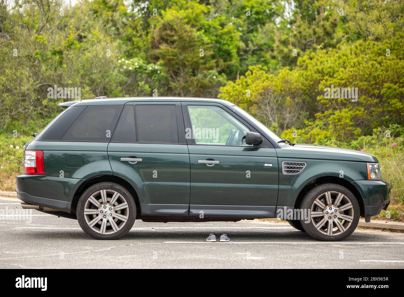 Green Range Rover at a Southampton beach with shoes sitting on the ground Stock Photo