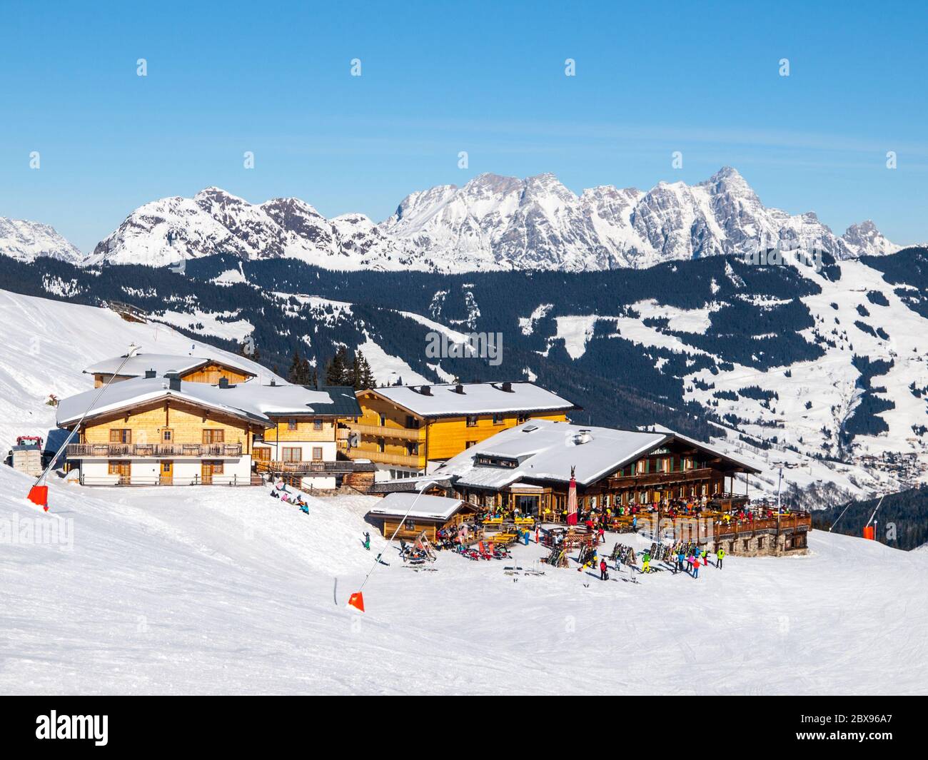 Downhill slope and apres ski mountain hut with restaurant terrace in Saalbach Hinterglemm Leogang winter resort, Tirol, Austria, Europe. Sunny day shot. Stock Photo