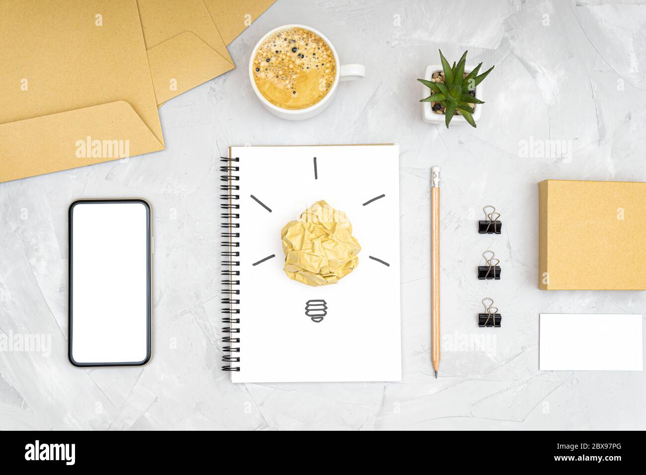 Refreshment break idea and productivity boost concept. Flat lay of an office workplace with a smartphone, coffee cup, light bulb symbol made of a crum Stock Photo