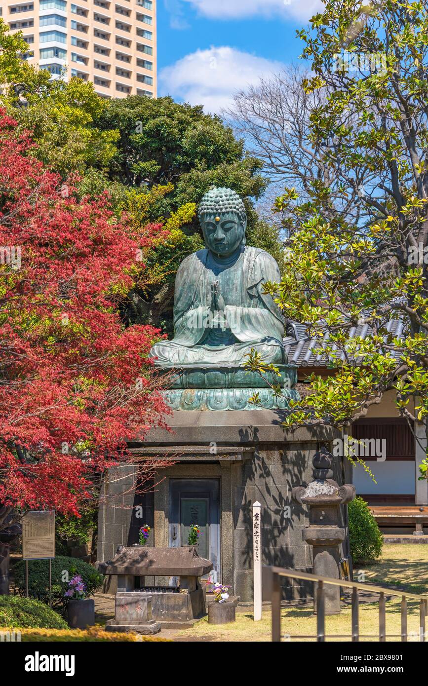 tokyo,japan - march 31 2020: Bronze statue of Buddha Shaka Nyorai with a stone lantern and the sentence May Peace Prevail On Earth on a Peace Pole Pro Stock Photo