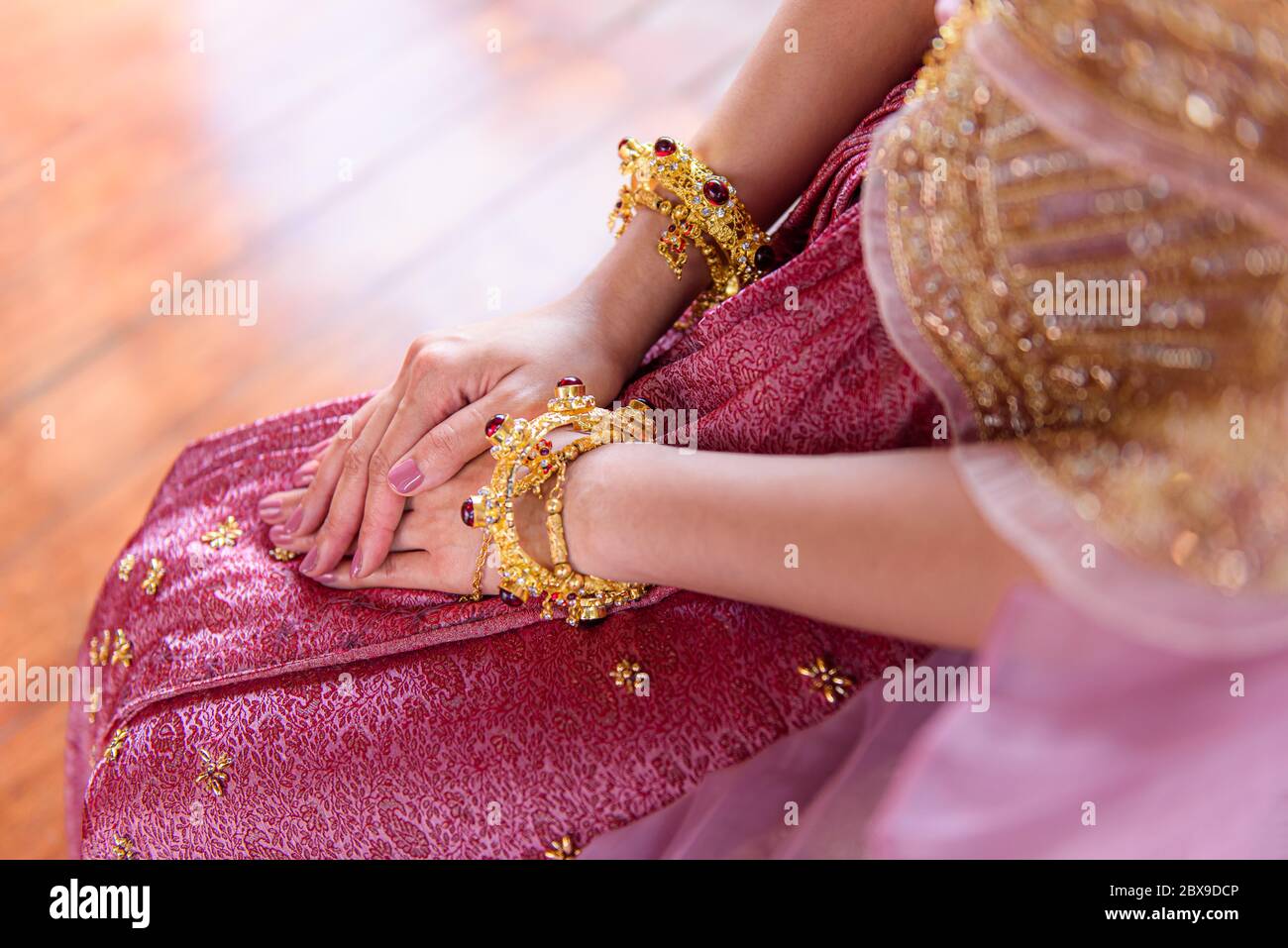 Asian Thai woman sitting with clasp hands legs crossed on the floor in traditional dress Stock Photo