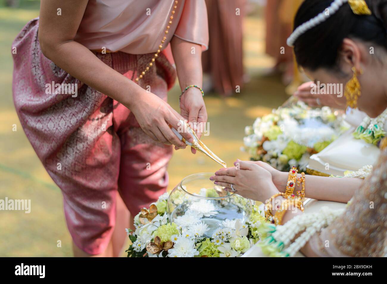 Holy water pouring ceremony over bride and groom hands, Thai traditional wedding engagement Stock Photo