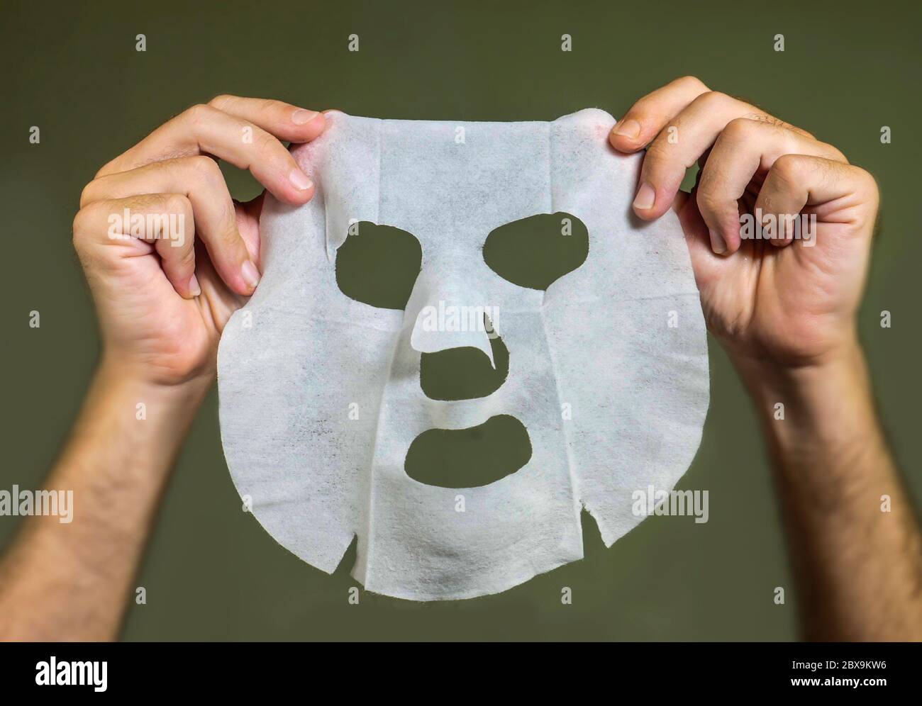 man hands holding beauty paper facial mask isolated on even background in face skin care concept Stock Photo